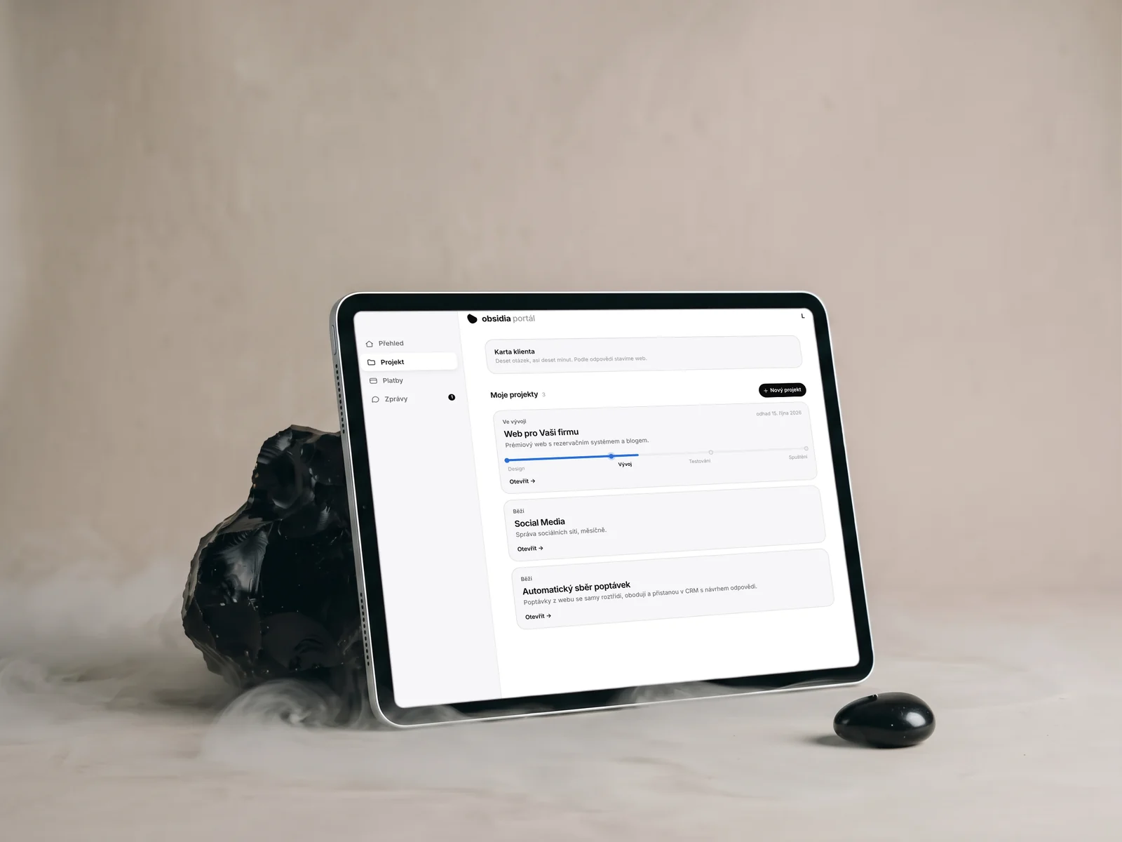 Klientský portál na tabletu vedle kusu obsidiánu, ukázková data