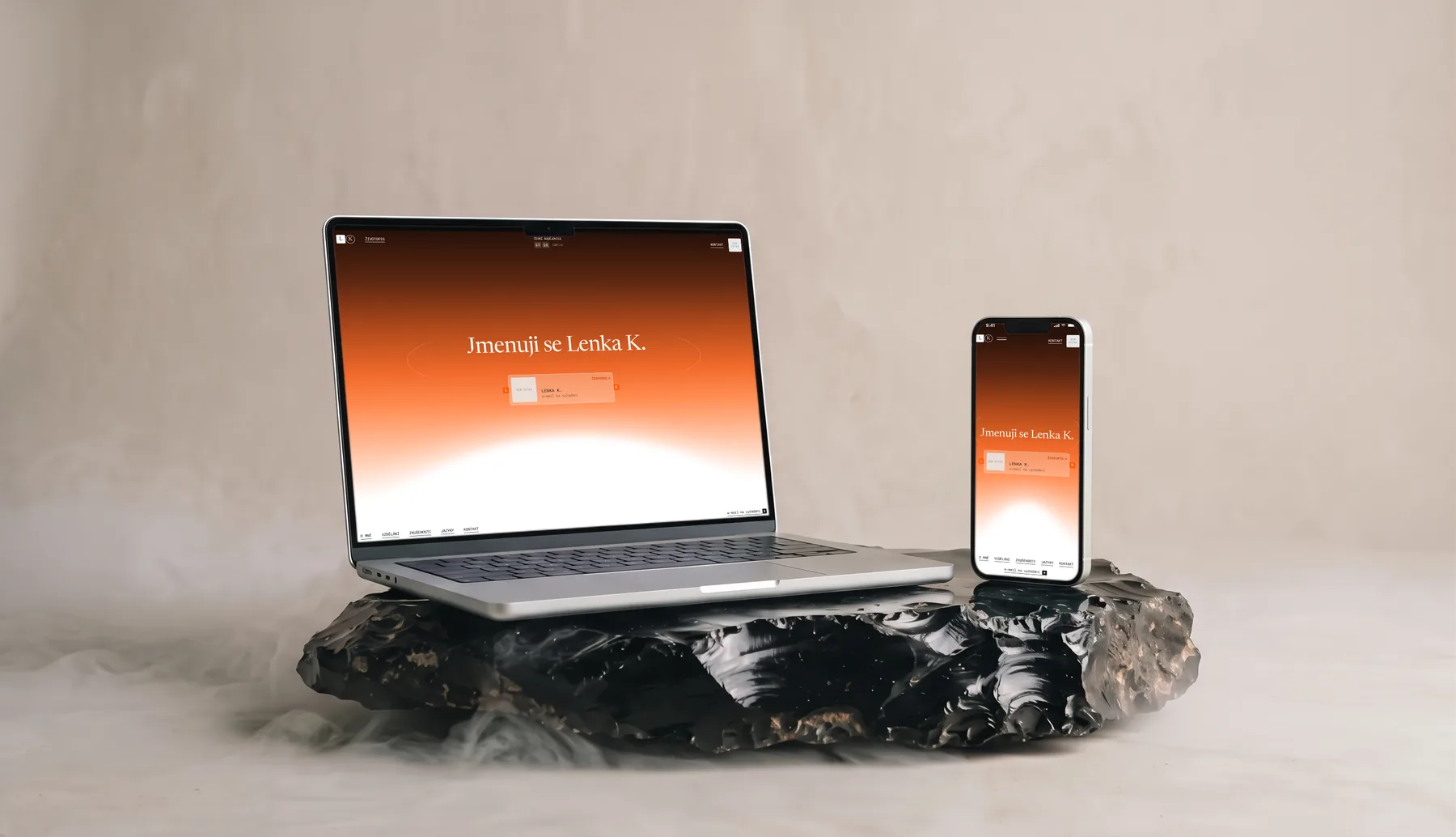 Web Lenky K. na notebooku a telefonu, položených na obsidiánu